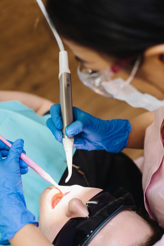 A dentist performs a procedure using modern dental equipment on a patient wearing protective glasses.